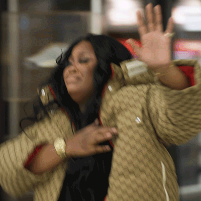 A Woman In A Gucci Jacket Is Waving Her Hand In The Air GIF