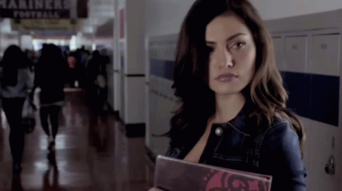 A Woman In A Hallway With A Sign That Says Mariners GIF