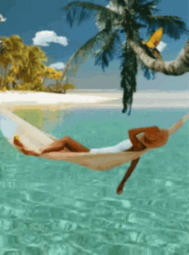 A Woman In A Hat Is Laying In A Hammock In The Ocean GIF