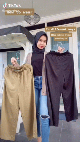 A Woman In A Hijab Is Holding A Pair Of Pants GIF