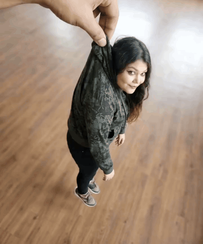 a woman in a hoodie is being held up by a man 's hand
