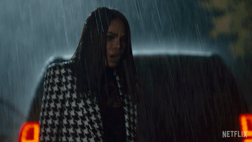 a woman in a houndstooth coat is standing in the rain next to a netflix logo