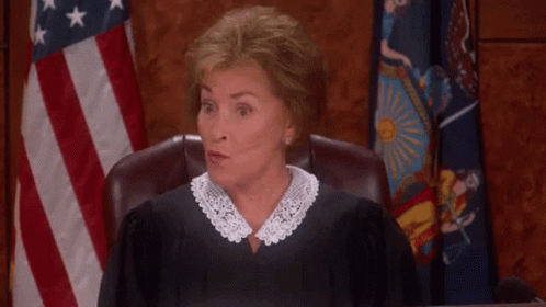 A Woman In A Judge 'S Robe Is Giving A Thumbs Up In Front Of An American Flag GIF