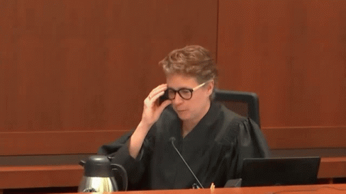 A Woman In A Judge 'S Robe Is Sitting At A Table In A Courtroom GIF