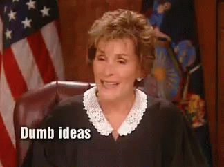 A Woman In A Judge 'S Robe Is Sitting In Front Of An American Flag . GIF