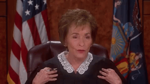 A Woman In A Judge 'S Robe Laughs In Front Of An American Flag GIF