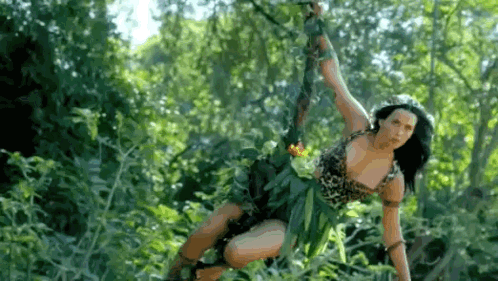 A Woman In A Jungle Outfit Is Hanging From A Rope In The Trees . GIF