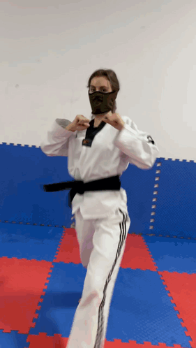 A Woman In A Karate Uniform Is Wearing A Black Mask GIF