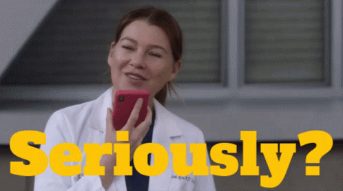 A Woman In A Lab Coat Is Holding A Cell Phone In Front Of The Words Seriously ? GIF