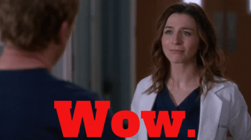 A Woman In A Lab Coat Is Standing Next To A Man And The Word Wow Is Visible In Red GIF