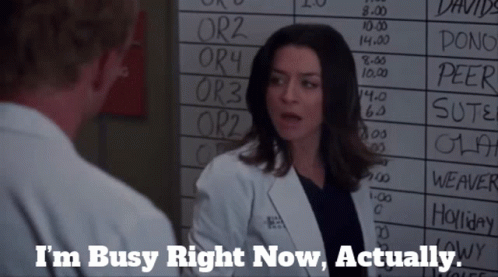 A Woman In A Lab Coat Is Talking To A Man In Front Of A White Board That Says I 'M Busy Right Now GIF