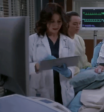 A Woman In A Lab Coat Is Using A Tablet GIF