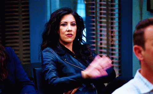 A Woman In A Leather Jacket Is Clapping Her Hands In A Room With Other People GIF