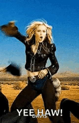 a woman in a leather jacket is dancing in the desert while wearing a hat .