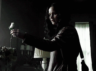 A Woman In A Leather Jacket Is Holding A Rose In Her Hand GIF