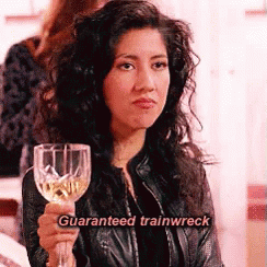 A Woman In A Leather Jacket Is Holding A Wine Glass With The Words `` Guaranteed Trainwreck '' Written On It . GIF