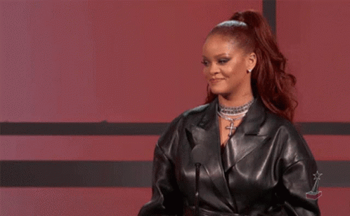 A Woman In A Leather Jacket Is Standing In Front Of A Microphone And Giving A Speech . GIF