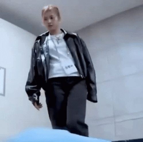 A Woman In A Leather Jacket Is Standing On A Blue Cushion . GIF
