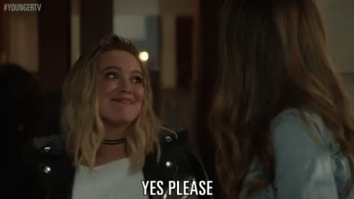 A Woman In A Leather Jacket Is Talking To Another Woman In A Room And Saying `` Yes Please '' . GIF
