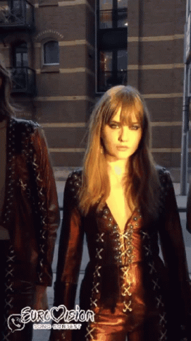 A Woman In A Leather Outfit With Eurovision Going Contest Written On The Bottom Right GIF