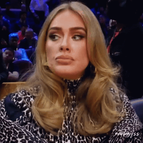 A Woman In A Leopard Print Dress Is Sitting In A Crowd Of People GIF