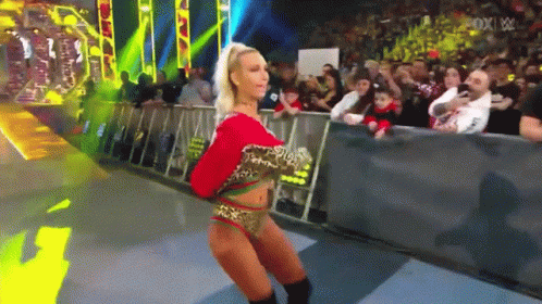A Woman In A Leopard Print Outfit Is Dancing In Front Of A Crowd At A Wrestling Show GIF
