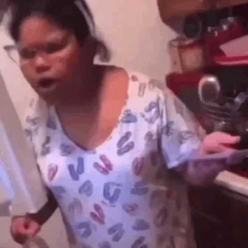 A Woman In A Leopard Print Shirt Is Standing In A Kitchen Holding A Knife . GIF