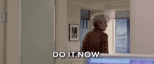 A Woman In A Leopard Print Shirt Is Standing In A Room . GIF
