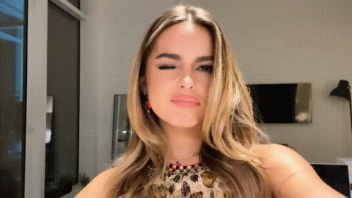 A Woman In A Leopard Print Top Is Taking A Selfie GIF