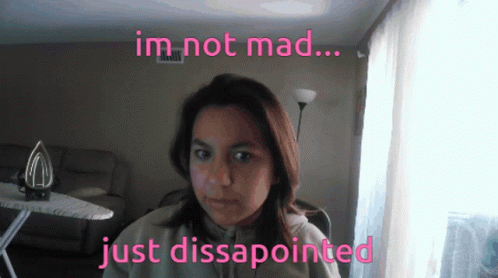 A Woman In A Living Room With The Words Im Not Mad Just Disappointed Above Her GIF