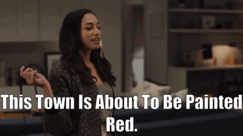 A Woman In A Living Room With The Words " This Town Is About To Be Painted Red " GIF
