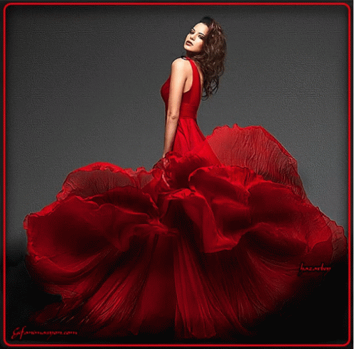 A Woman In A Long Red Dress Is Standing In Front Of A Black Background GIF
