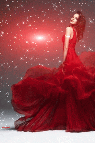 A Woman In A Long Red Dress Is Standing In Front Of A Red Background GIF