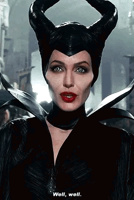 A Woman In A Maleficent Costume With Horns On Her Head Is Talking To Someone . GIF