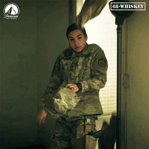 A Woman In A Military Uniform Is Holding A Helmet In Front Of A Paramount Network Logo GIF