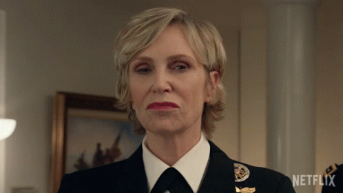 A Woman In A Military Uniform Is Standing In Front Of A Netflix Logo GIF