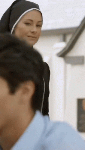 A Woman In A Nun 'S Habit Stands Next To A Man In A Blue Shirt . GIF