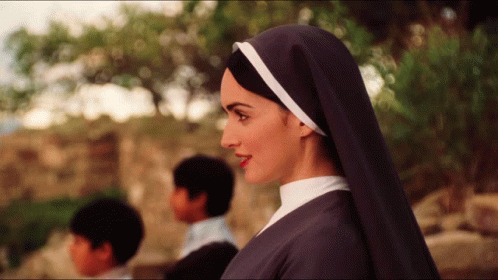 A Woman In A Nun 'S Veil Stands In Front Of Two Children GIF