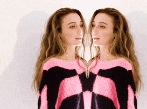 A Woman In A Pink And Black Striped Sweater Is Standing Next To Another Woman GIF