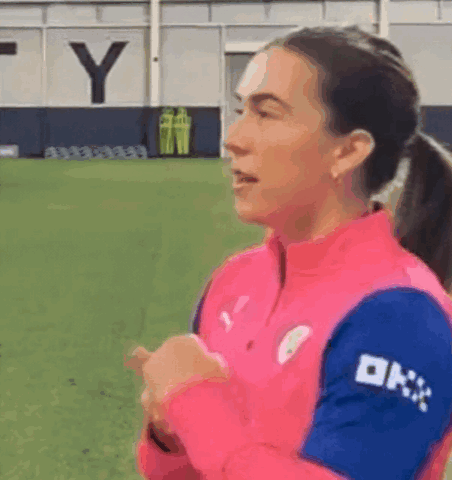 A Woman In A Pink And Blue Shirt With The Word Ok On Her Sleeve GIF