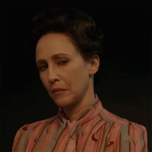 A Woman In A Pink And Gray Striped Shirt Is Making A Funny Face . GIF