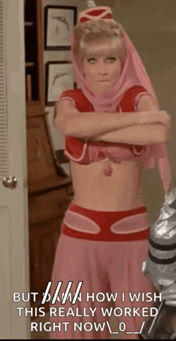 A Woman In A Pink And Red Costume With Her Arms Crossed Is Standing In A Room With A Door . GIF
