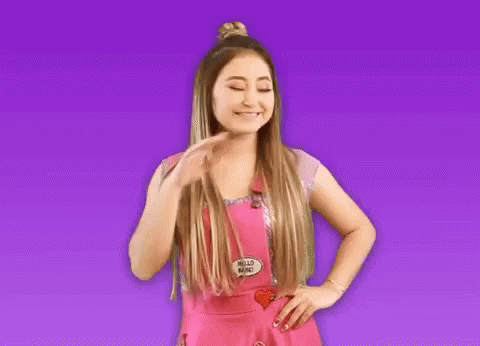 A Woman In A Pink Apron With A Hello Babe Pin On It GIF