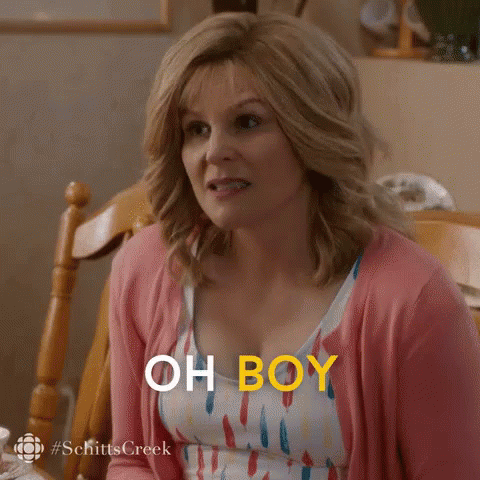 A Woman In A Pink Cardigan Is Sitting At A Table And Says `` Oh Boy '' . GIF