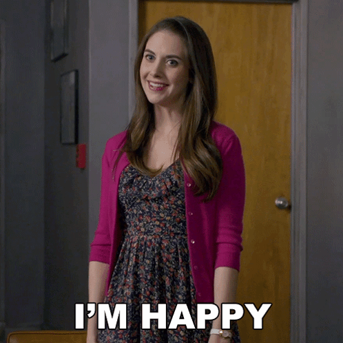 A Woman In A Pink Cardigan Says I 'M Happy In Front Of A Door GIF