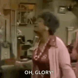 A Woman In A Pink Coat Is Standing In A Living Room . GIF
