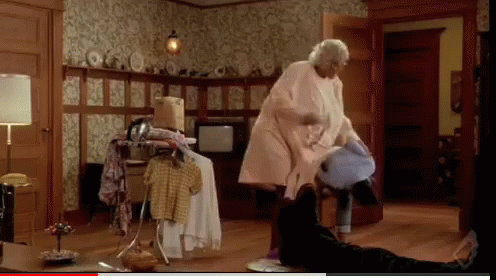 A Woman In A Pink Coat Is Standing In A Room GIF