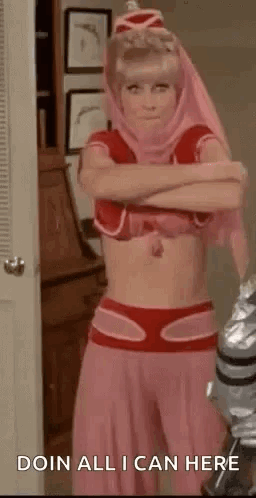A Woman In A Pink Costume Is Standing In A Room With Her Arms Crossed And A Robot In The Background . GIF