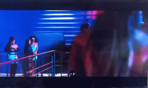 A Woman In A Pink Crop Top Is Dancing In Front Of A Crowd GIF