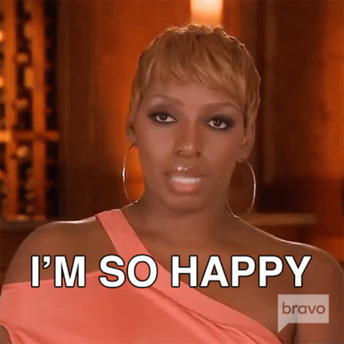 A Woman In A Pink Dress And Hoop Earrings Is Saying I 'M So Happy . GIF